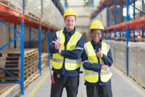 Happy staff in warehouse in safety jackets using technology recommended by Thera Solutions Group