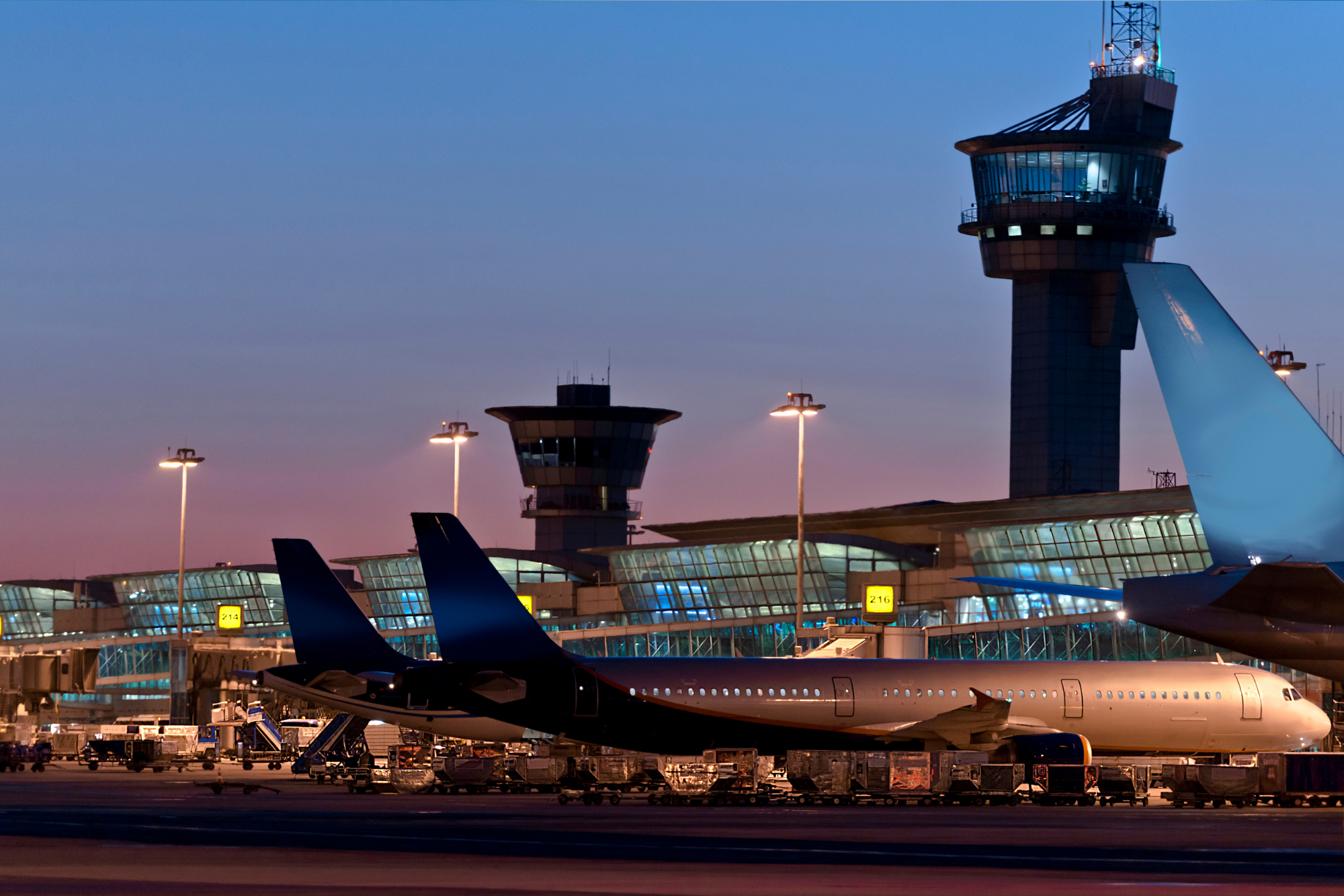 Busy airport with planes parked on the tarmac near the terminal. Hey, you could also se the tower! It's a really cool night-time shot!